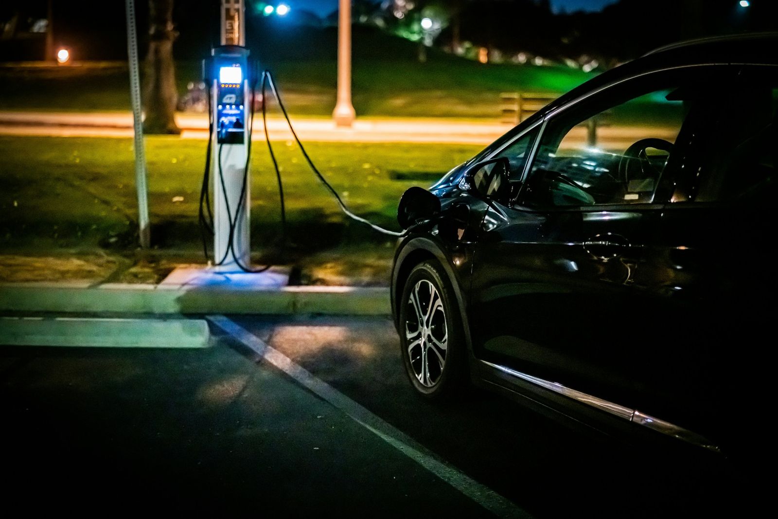 EV charging station charging a car in a parking lot at night